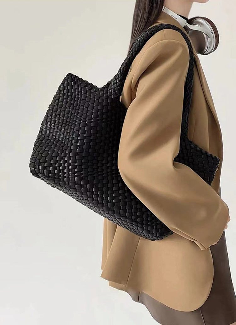 Black woven tote bag worn over shoulder with large open top